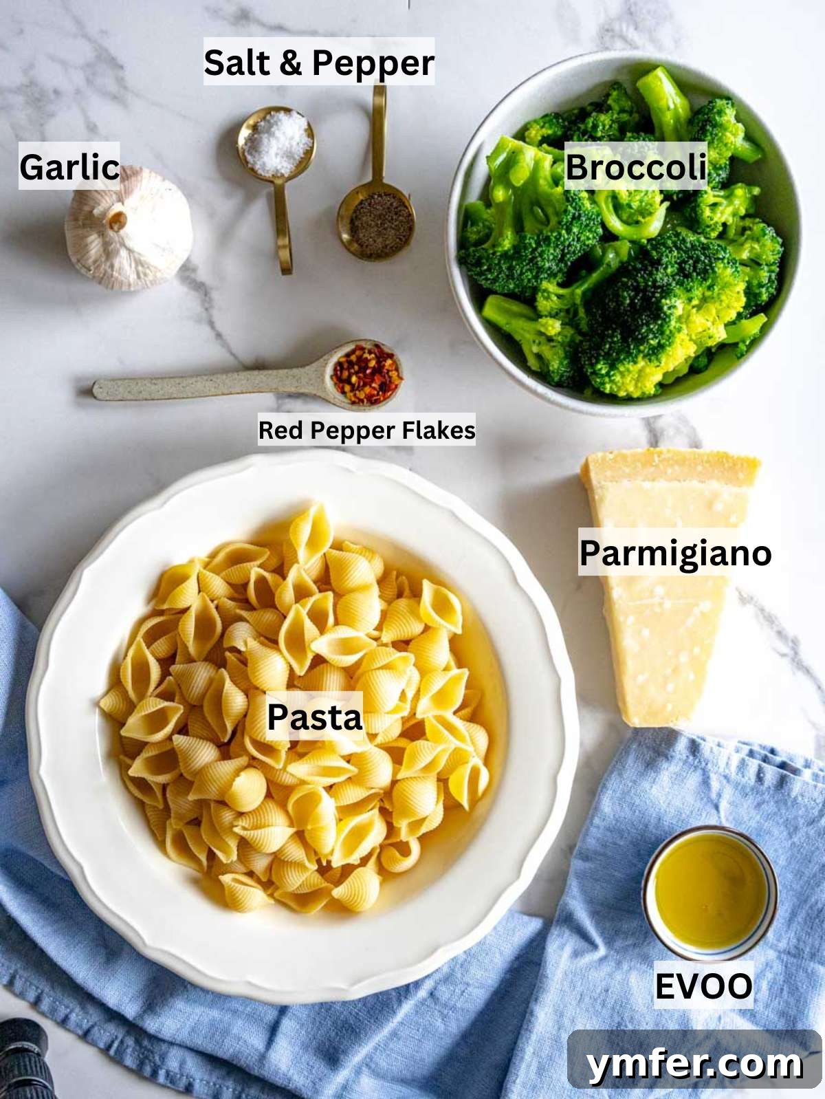 Fresh broccoli pasta garlic parmesan basil and olive oil arranged on a wooden board.