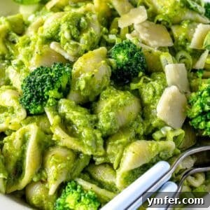 Bowl of smashed broccoli pasta with parmesan cheese and basil ready to serve.
