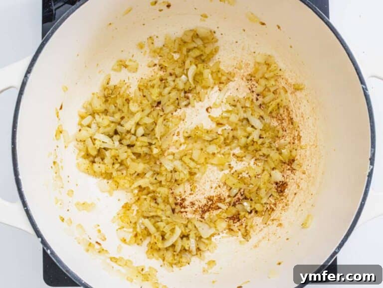 Nourishing Creamy Coconut Pumpkin Soup for Fall 13 Step 3 Onion garlic and ginger sautéing in a pot with olive oil and red pepper flakes.