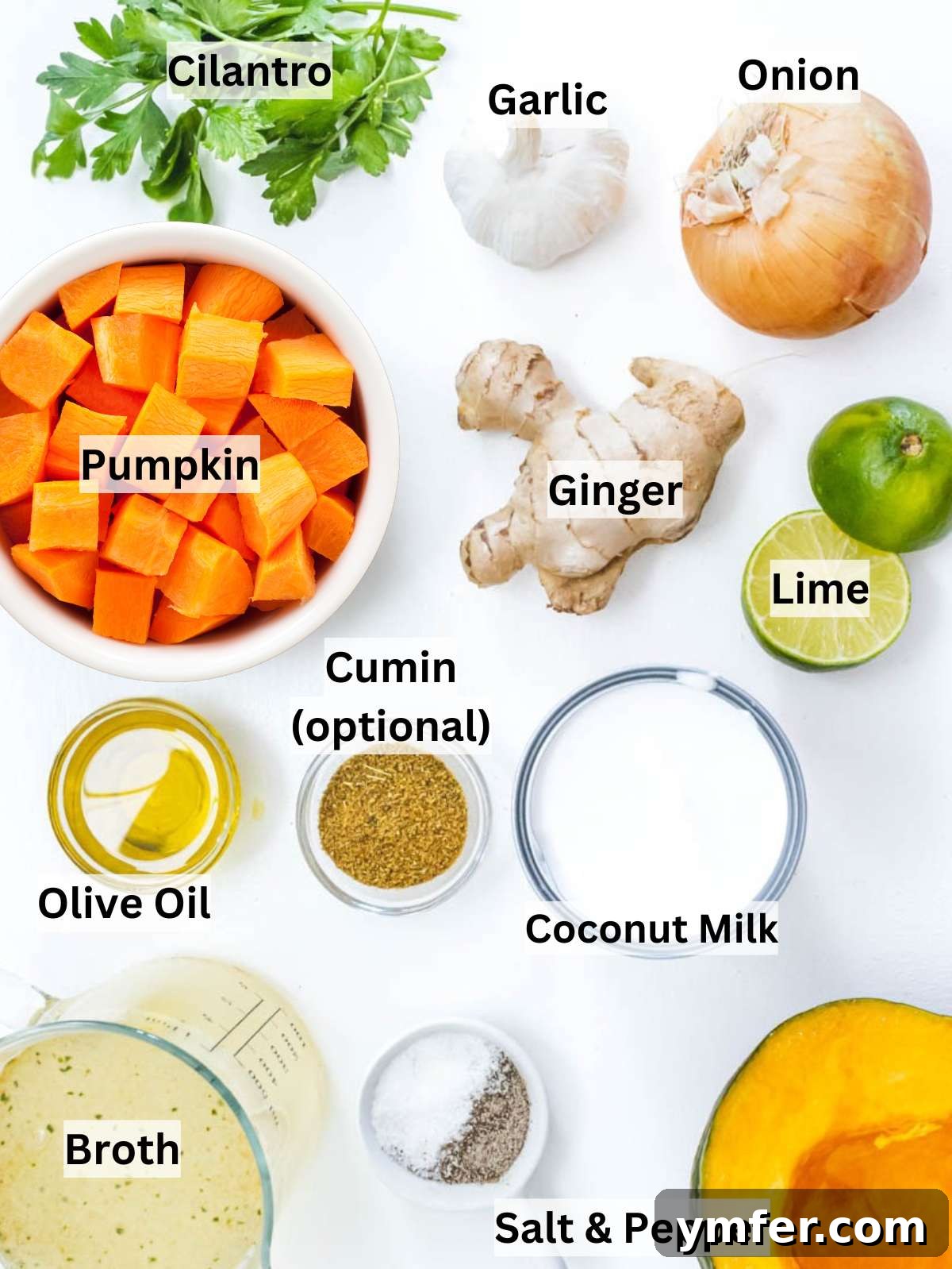 Nourishing Creamy Coconut Pumpkin Soup for Fall 3 Ingredients for creamy coconut pumpkin soup laid out on a table, including pumpkin, onion, garlic, ginger, coconut milk, and lime, ready for preparation.