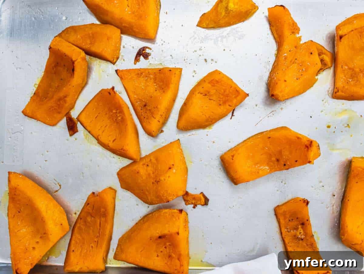 Nourishing Creamy Coconut Pumpkin Soup for Fall 6 Step 2 Roasted pumpkin pieces, golden-brown and tender, fresh from the oven on a baking tray, radiating warmth and flavor.