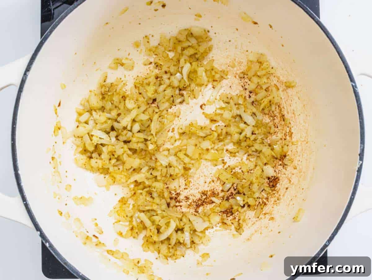Nourishing Creamy Coconut Pumpkin Soup for Fall 7 Step 3 Aromatic blend of onion, garlic, and ginger sautéing in a pot with olive oil and red pepper flakes, filling the kitchen with rich scents.