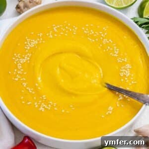 Nourishing Creamy Coconut Pumpkin Soup for Fall 10 Cozy fall dinner with creamy coconut pumpkin soup in a rustic kitchen setting, beautifully presented in a white bowl with fresh garnishes.