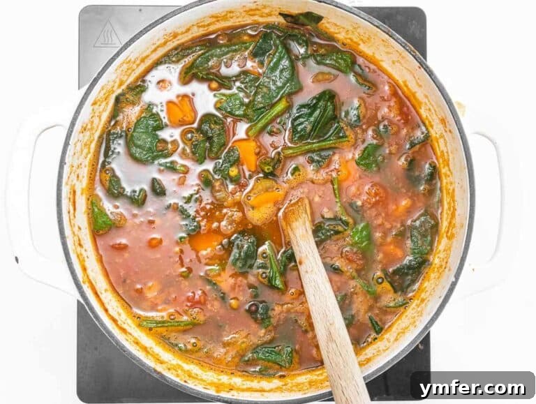 Step 3 Stirring fresh spinach into the soup until wilted.