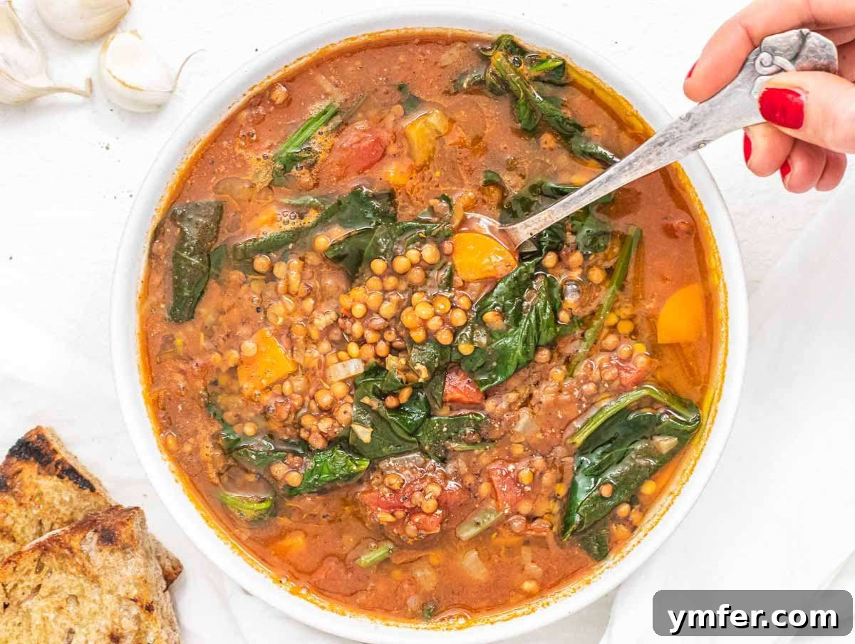 Nourishing Spinach Lentil Soup Easy Dinner 7 Step 4 Serving spinach lentil soup in a bowl with a lemon wedge and a slice of crusty bread, ready to enjoy.