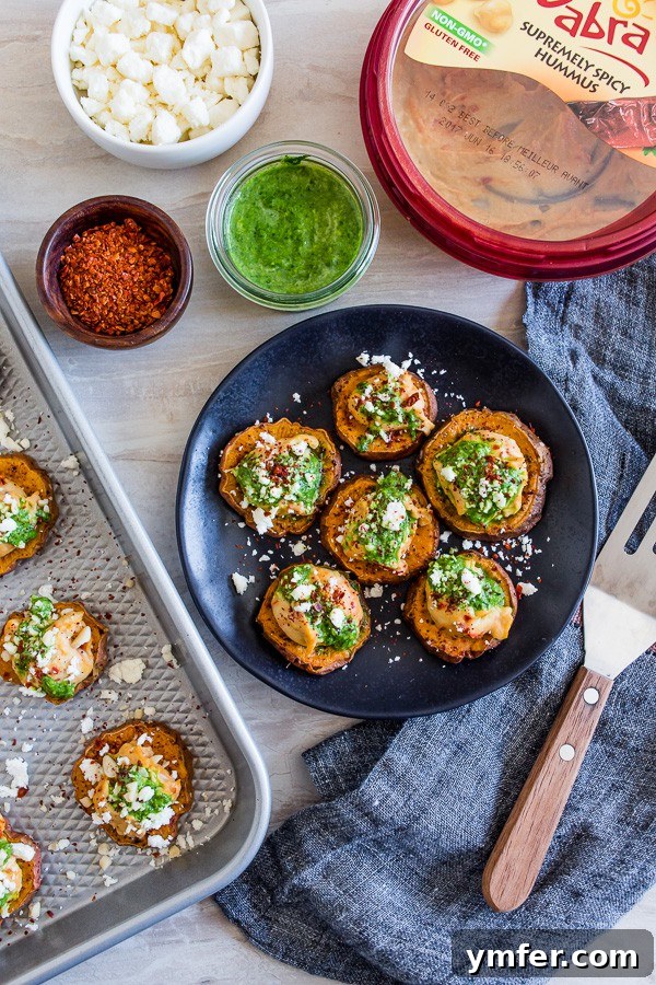 Vibrant Pesto Hummus Sweet Potato Rounds 2 Close-up of vibrant Pesto Hummus Sweet Potato Bites on a serving platter, showing golden sweet potato, creamy hummus, green pesto, and white feta.