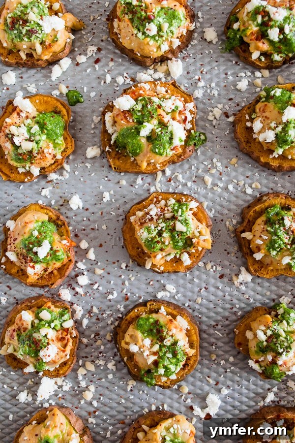Vibrant Pesto Hummus Sweet Potato Rounds 4 Several Pesto Hummus Sweet Potato Bites arranged neatly on a cutting board, garnished with fresh herbs.