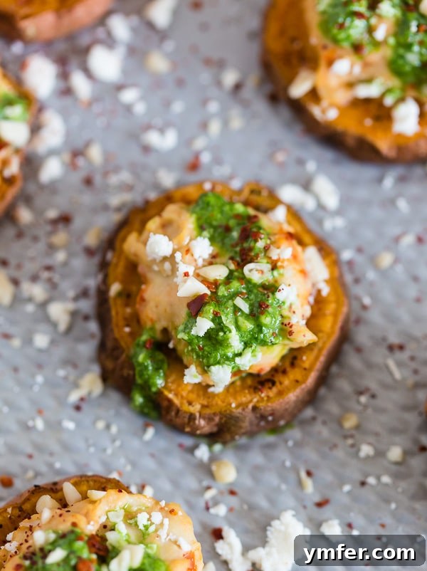 Vibrant Pesto Hummus Sweet Potato Rounds 6 A hand reaching for a Pesto Hummus Sweet Potato Bite, illustrating its irresistible appeal as a snack.