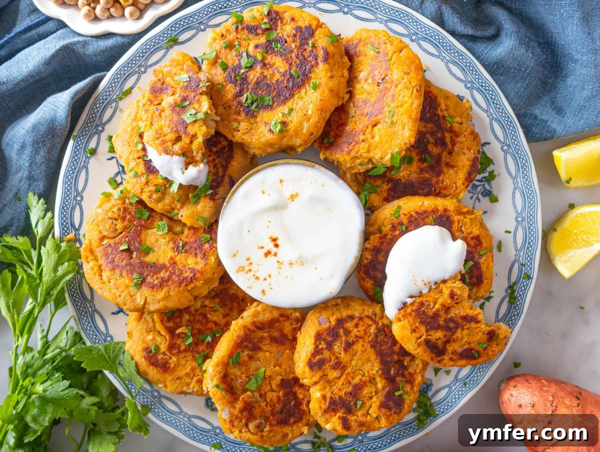 Simple Wholesome Chickpea Sweet Potato Patties 8 Step 4 – A plate of freshly cooked chickpea sweet potato fritters, served beautifully with a side of creamy yogurt sauce and a wedge of lemon for a final squeeze.