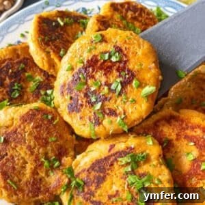 Simple Wholesome Chickpea Sweet Potato Patties 9 Stack of crispy chickpea sweet potato patties on a white and blue plate with fresh herbs for garnish.