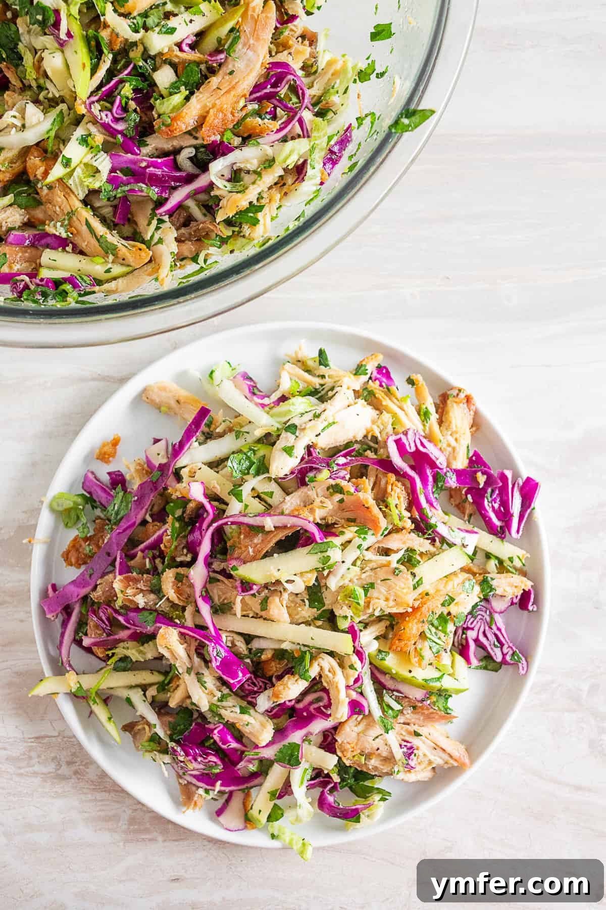 Vibrant Crispy Chicken Slaw 5 Crispy Chicken Cabbage Salad on a white plate, garnished with sprigs of fresh herbs.