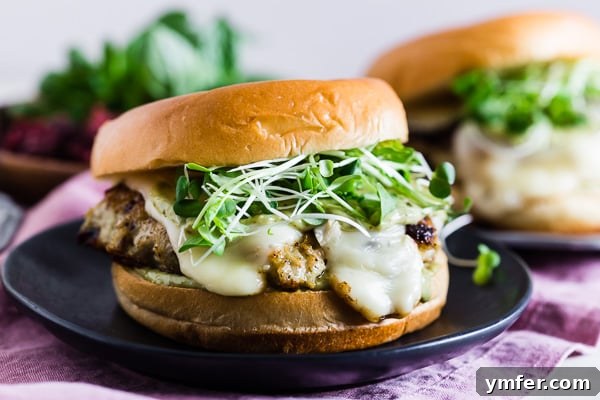Sweet & Savory Cranberry Pesto Chicken Burgers 4 Three Cranberry Pesto Chicken Burgers on a cutting board, garnished with fresh microgreens and ready to serve.