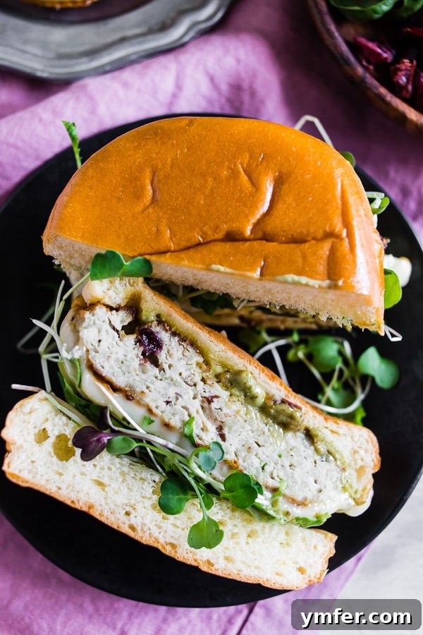 Sweet & Savory Cranberry Pesto Chicken Burgers 5 A perfectly cooked Cranberry Pesto Chicken Burger with melted Brie and microgreens, ready to be served on a brioche bun.