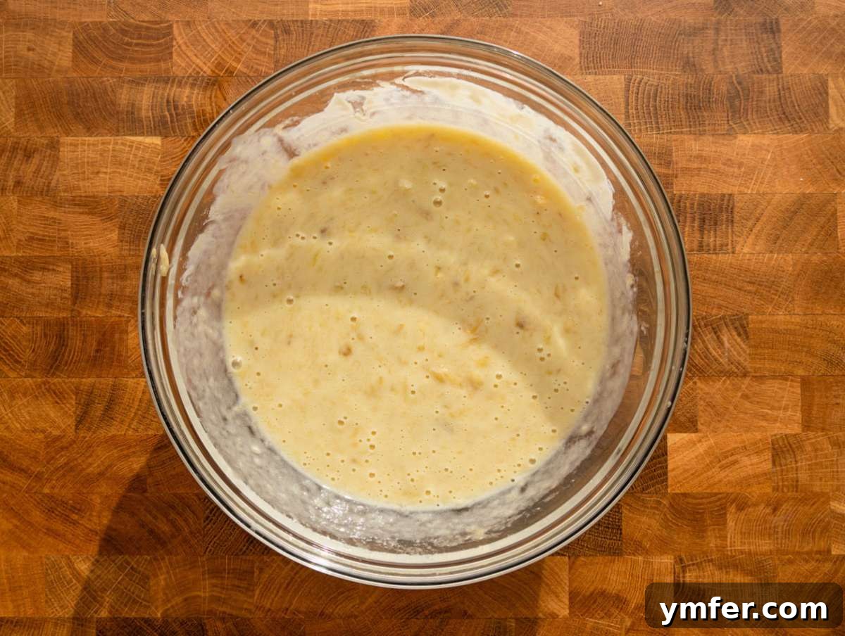 Wholesome Oil-Free Banana Oat Muffins 5 Step 1 Mashed ripe banana mixed with egg Greek yogurt honey and vanilla extract in a bowl.