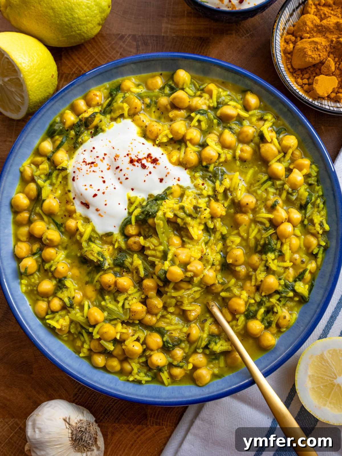 Golden Turmeric Chickpea Rice 4 Golden turmeric rice with chickpeas and spinach served in a bowl with lemon wedge squeezed on top.