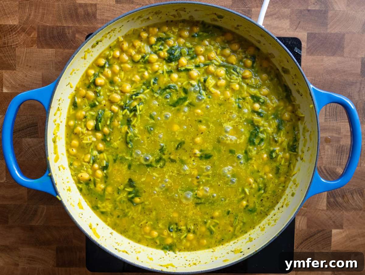 Golden Turmeric Chickpea Rice 7 Step 3 Stirring basmati rice and chickpeas in fragrant broth for a creamy one pot Mediterranean recipe.