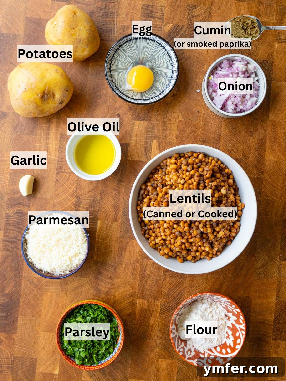Simple, fresh ingredients laid out for making lentil potato patties, including canned lentils, a potato, flour, parmesan cheese, an egg, red onion, garlic, cumin, and fresh parsley.