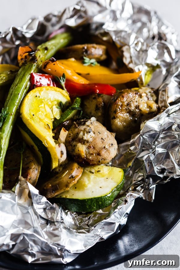 Hearty Chicken Sausage and Roasted Veggie Foil Bundles 7 A single portion of the chicken sausage and vegetable foil packet dinner, garnished with fresh herbs.