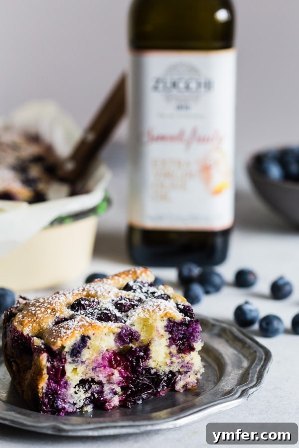 Mediterranean Blueberry Citrus Ricotta Cake 4 Blueberry Lemon Ricotta Olive Oil Cake sliced on a small dessert plate. Served beautifully with a fork.