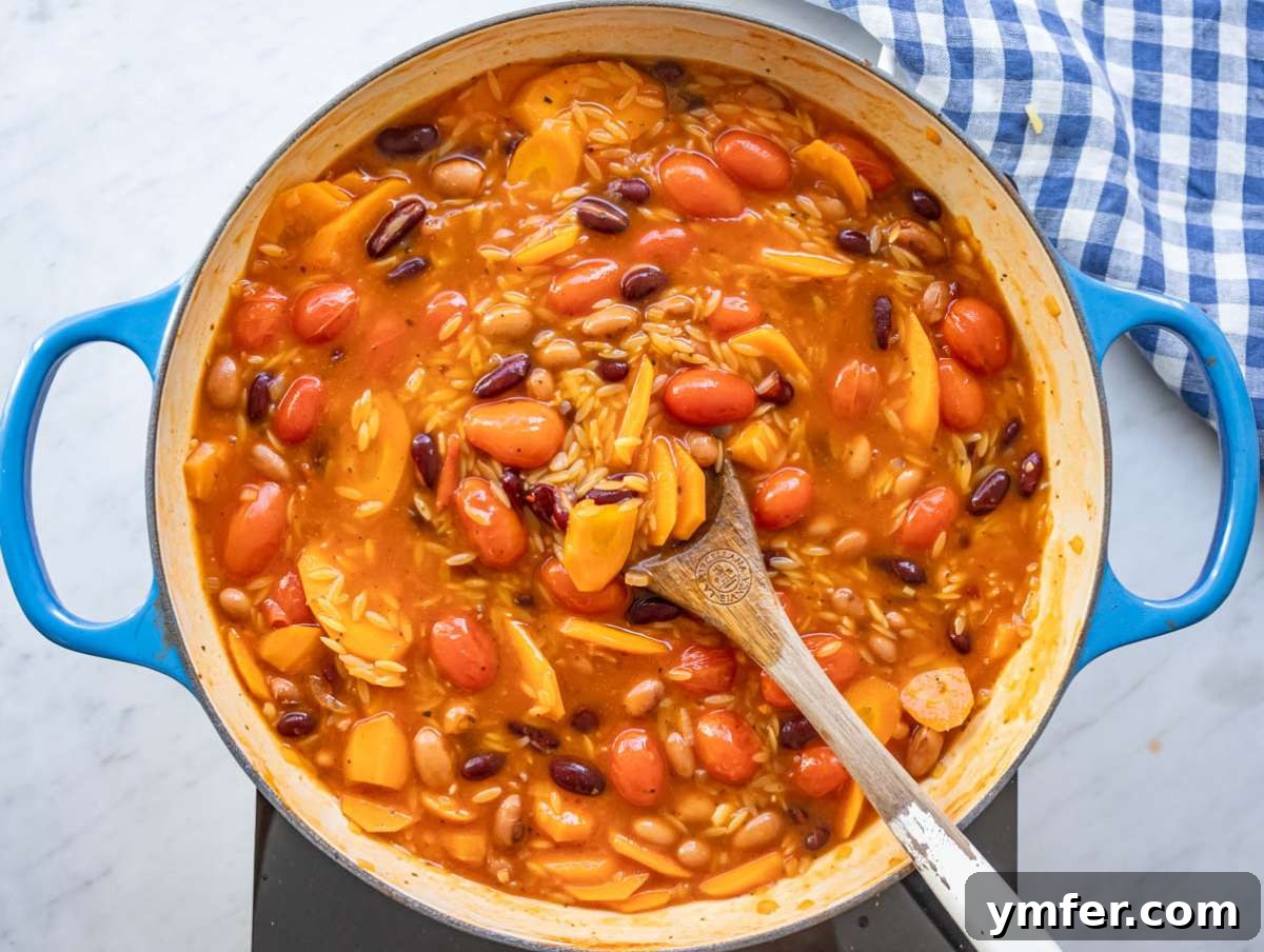 Mediterranean Orzo with Beans A Wholesome One-Pan Meal 8 Step 4 adding orzo to simmering pot for creamy one pot orzo recipe.
