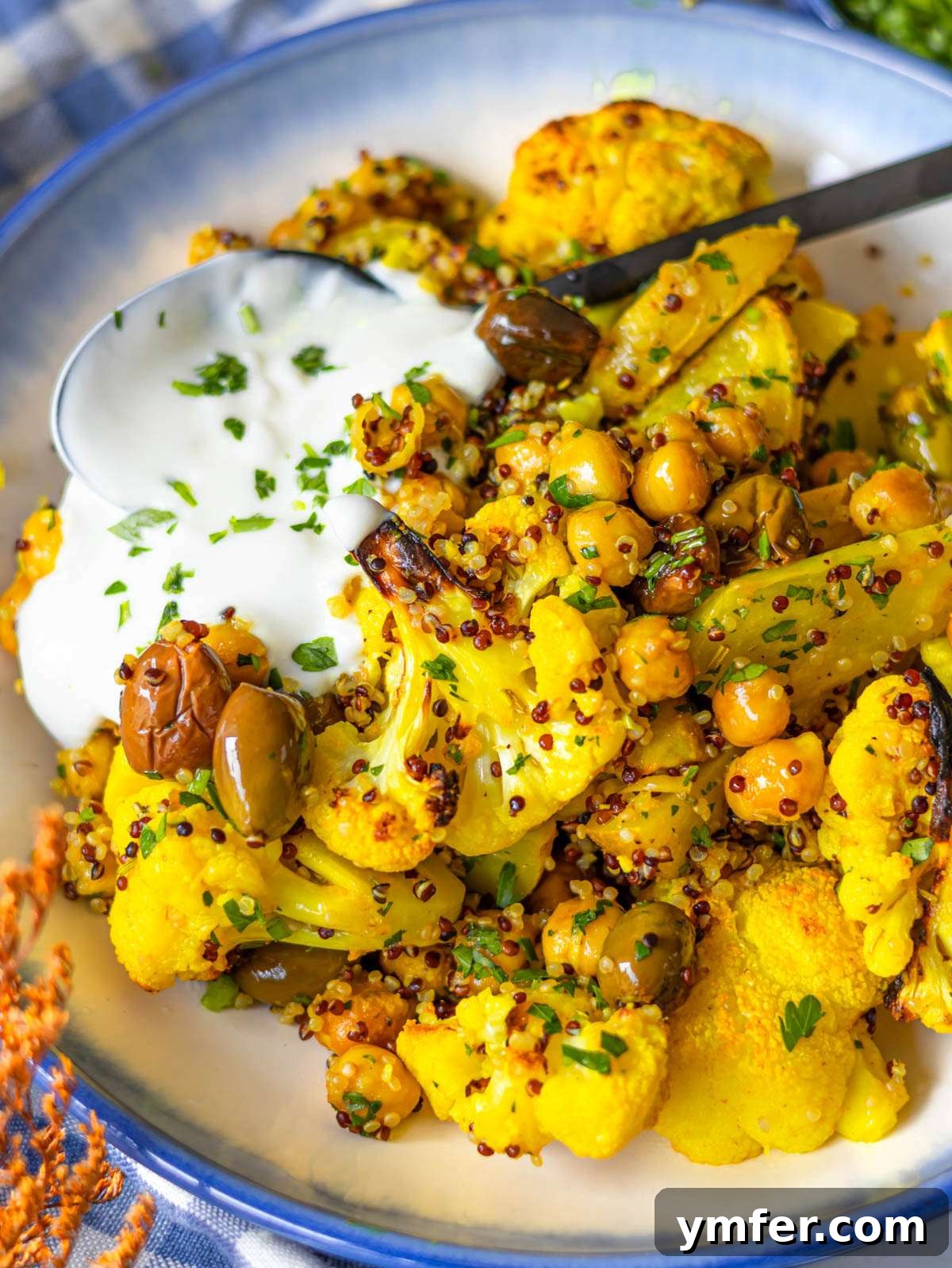 Golden Turmeric Cauliflower and Chickpea Sheet Pan Dinner 2 Finished turmeric cauliflower and chickpeas with quinoa and yogurt in a bowl.