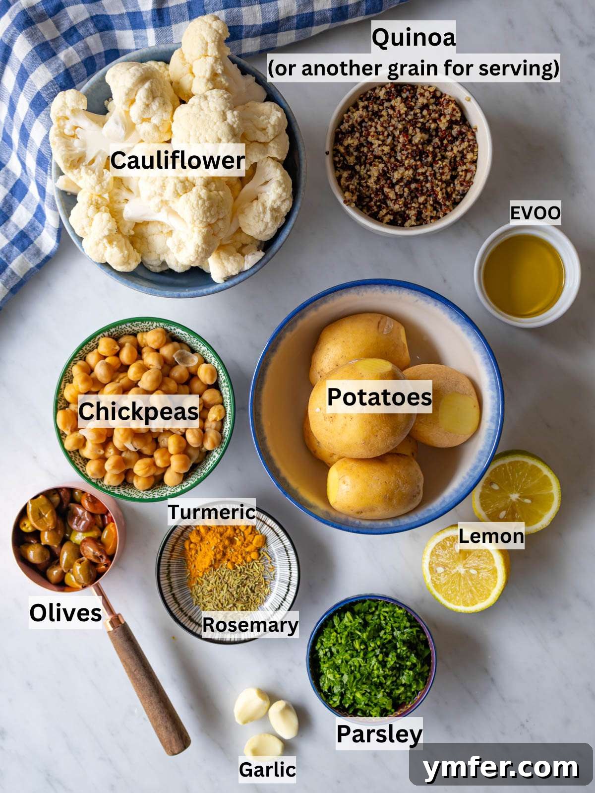 Golden Turmeric Cauliflower and Chickpea Sheet Pan Dinner 3 Ingredients shot cauliflower potatoes chickpeas olives spices and lemon arranged on table.