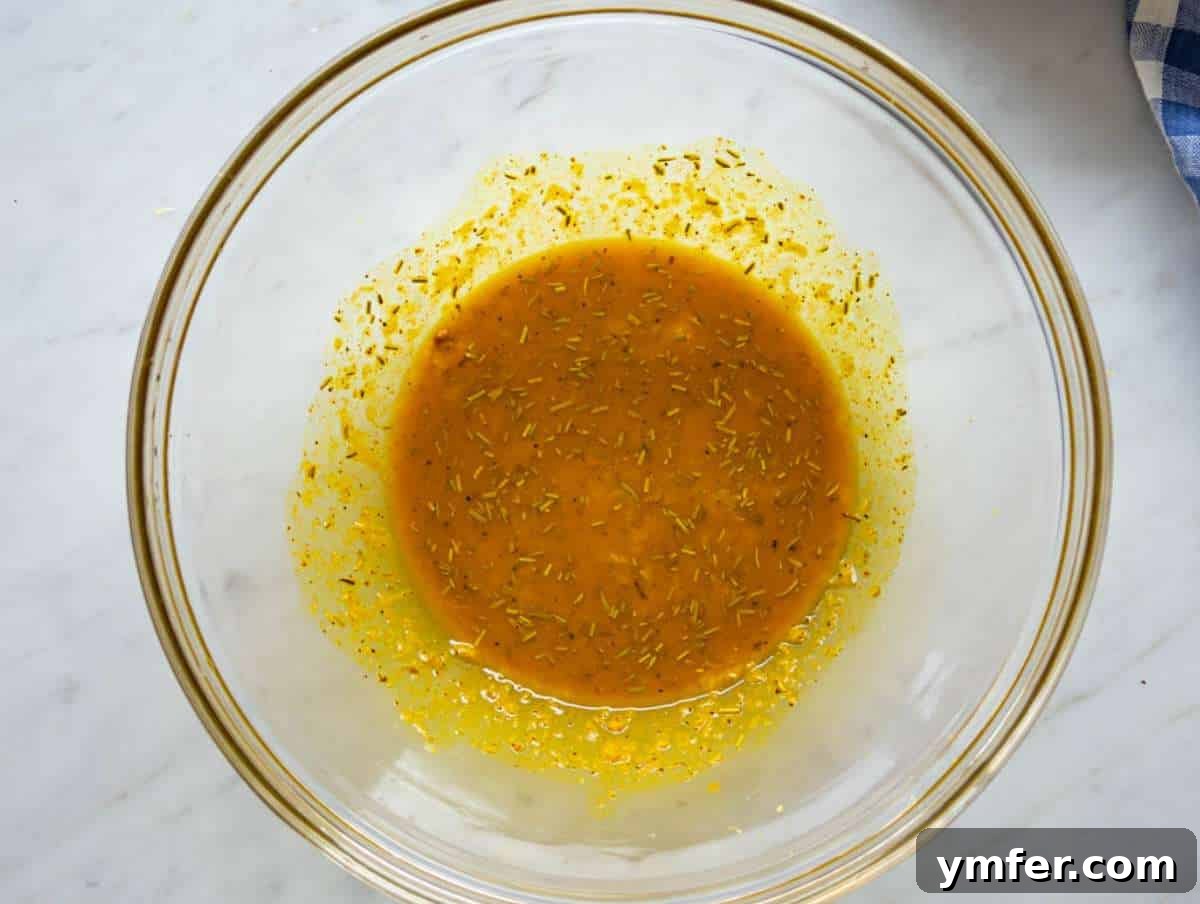 Golden Turmeric Cauliflower and Chickpea Sheet Pan Dinner 5 Step one whisking turmeric marinade with garlic lemon rosemary in bowl.