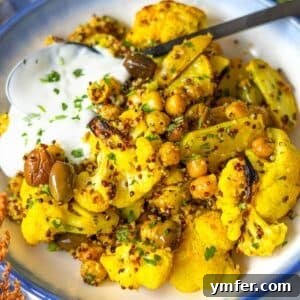 Golden Turmeric Cauliflower and Chickpea Sheet Pan Dinner 9 Bowl of vibrant turmeric cauliflower and chickpea sheet pan dinner with fresh herbs.