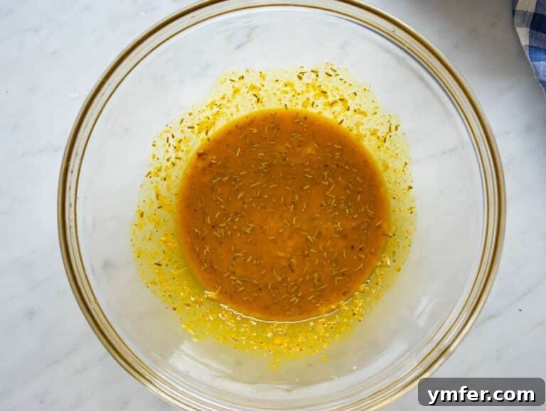 Golden Turmeric Cauliflower and Chickpea Sheet Pan Dinner 10 Step one whisking turmeric marinade with garlic lemon rosemary in bowl.