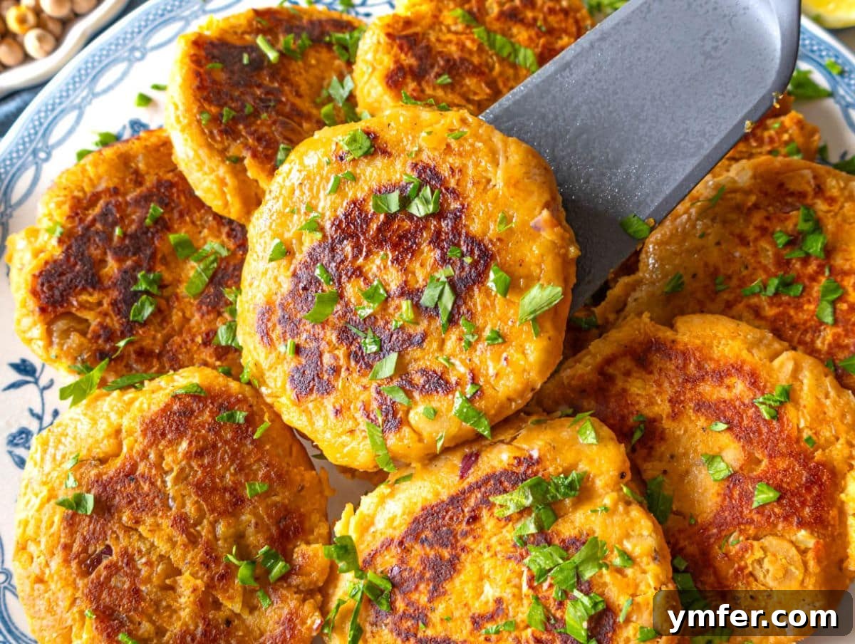 Fuel Up Fast: 25 High-Protein Bean Recipes in 30 Minutes 8 Healthy chickpea sweet potato patties on a marble table with dip and lemon wedges.