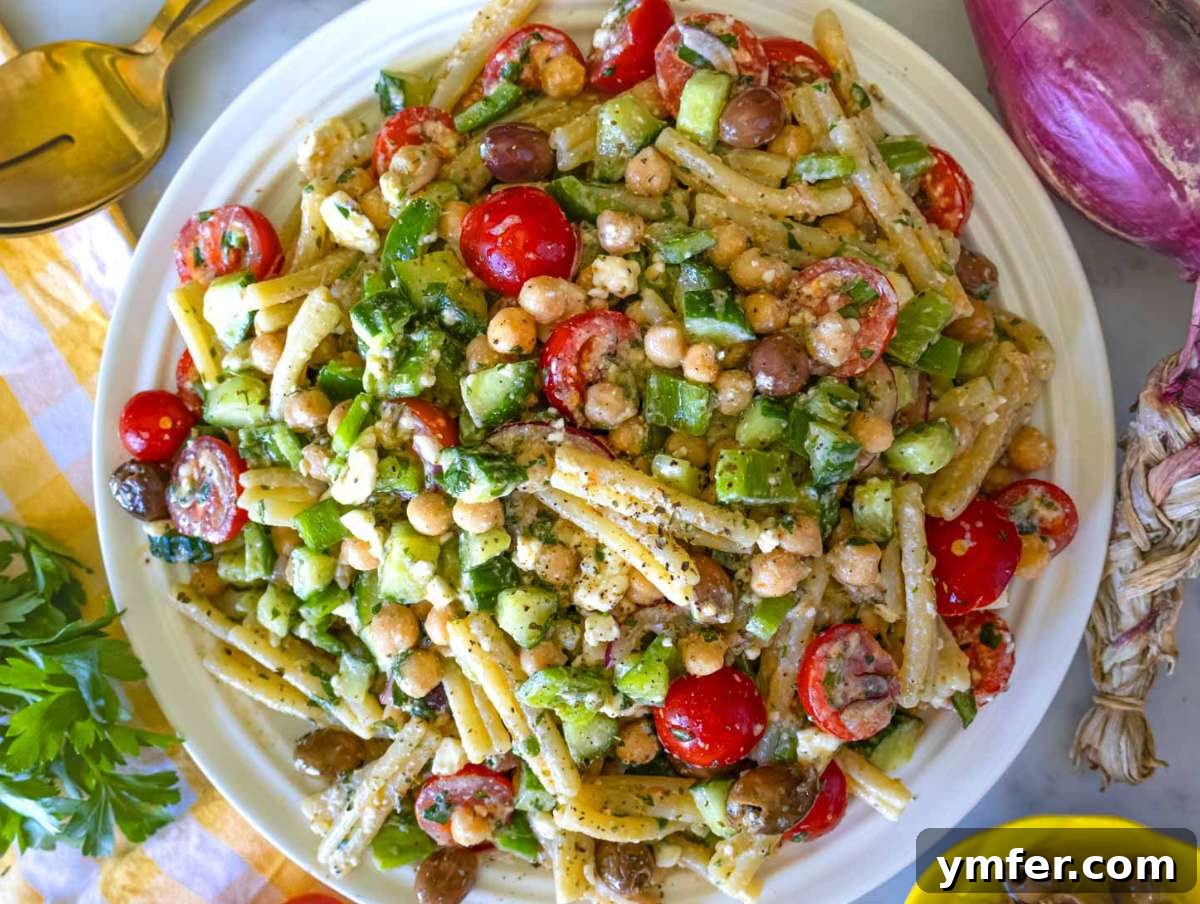 25 Affordable and Healthy Mediterranean Diet Meals 19 Step picture 4 Serving the Greek pasta salad on a white platter.