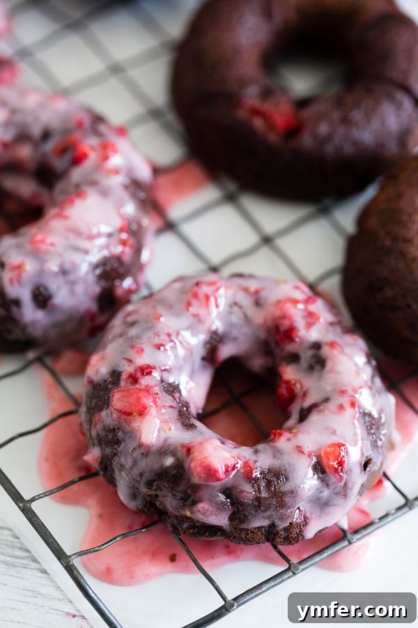 Decadent Chocolate Strawberry Donuts 4 Freshly baked chocolate strawberry donuts cooling on a rack, ready for their delicious homemade strawberry glaze. An easy and fun baking project.