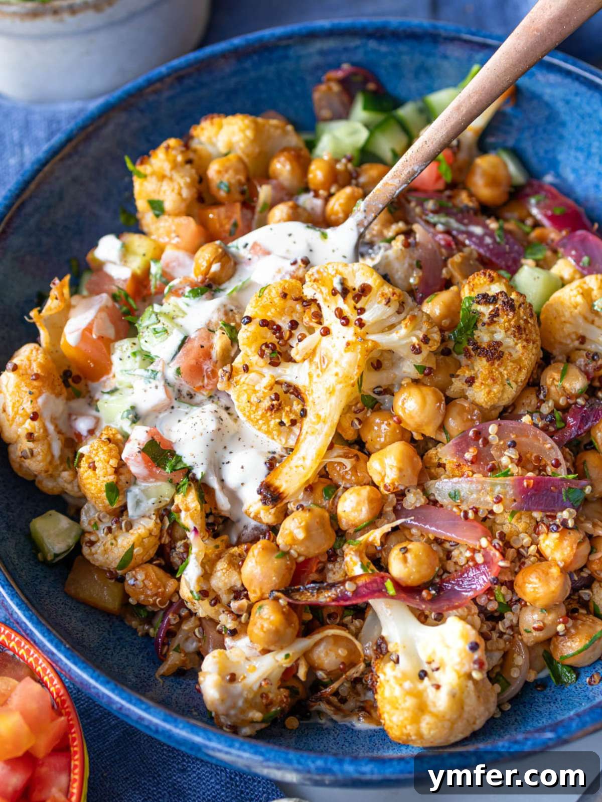 Cauliflower shawarma bowl with colorful vegetables herbs and creamy lemon sauce.