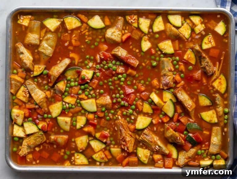 Effortless One-Pan Vegetable Paella 11 Step two Warm broth poured over seasoned rice and vegetables on sheet pan.