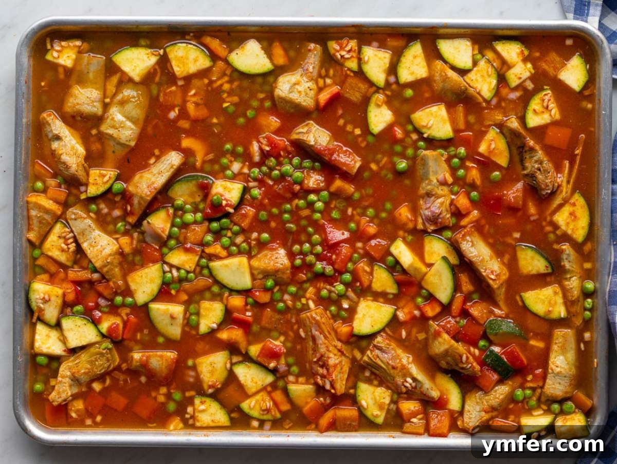 Effortless One-Pan Vegetable Paella 6 Step two Warm broth poured over seasoned rice and vegetables on sheet pan.