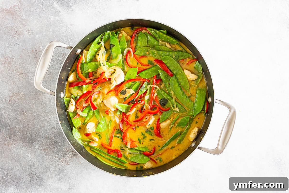 Emerald Chicken Curry 5 Green Chicken Curry simmering in a round cooking skillet, showcasing its rich texture.