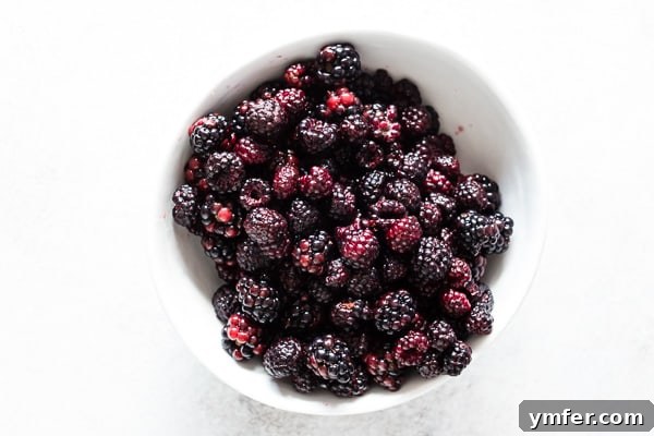 Berry Burst Coffee Cake 3 A rustic ceramic bowl brimming with a colorful assortment of fresh blackberries and black raspberries, perfectly ripe and ready to be incorporated into the coffee cake.