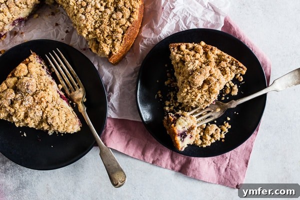 Berry Burst Coffee Cake 5 Two enticing slices of berry coffee cake adorned with streusel, presented on a stylish black plate, ready to be enjoyed with a cup of coffee.