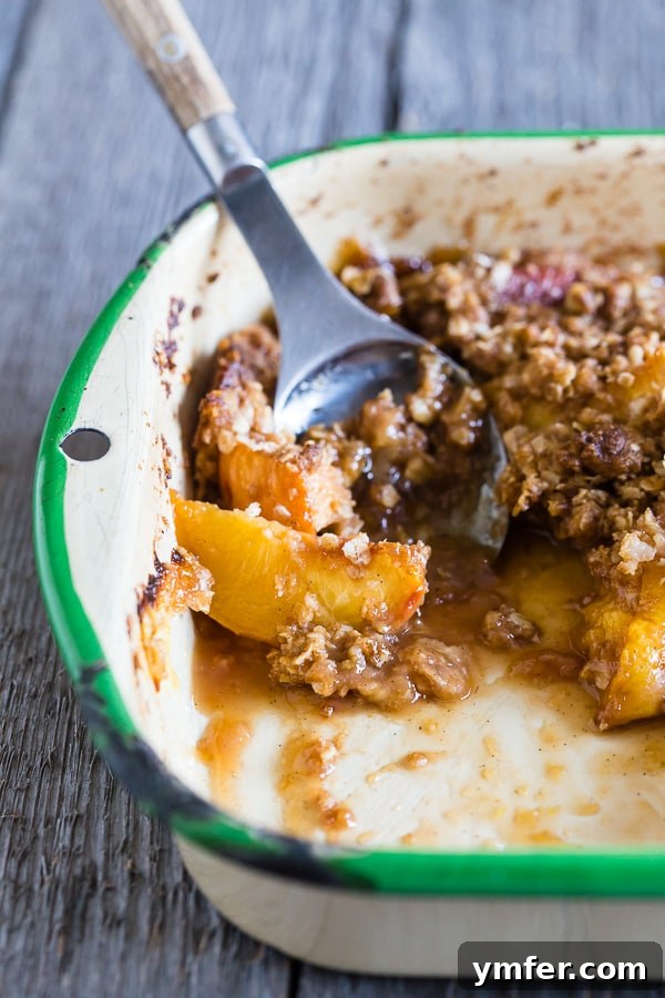 Zesty Ginger Peach Crisp 6 A ginger peach crisp, fresh out of the oven, with a small portion scooped out, showing the warm, bubbly peach filling.