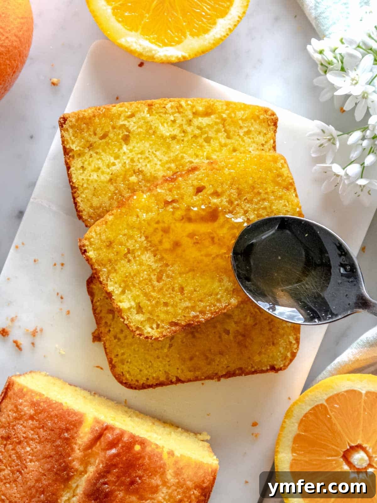 Zesty Orange Bliss Cake 4 A close-up of a slice of orange cake, glistening with warm orange syrup being drizzled over it.