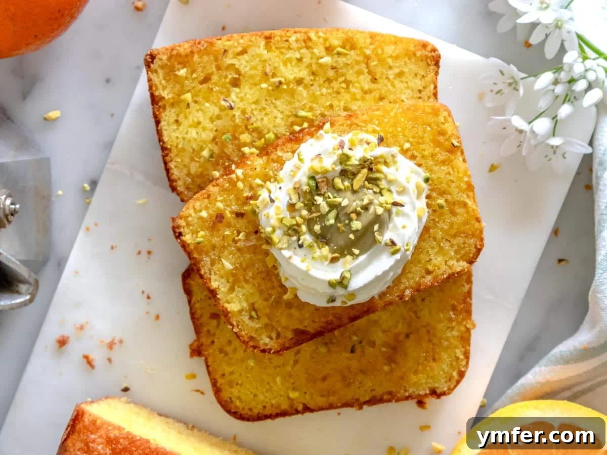 Zesty Orange Bliss Cake 8 A slice of orange cake beautifully garnished with whipped cream, pistachio butter, and chopped pistachios.