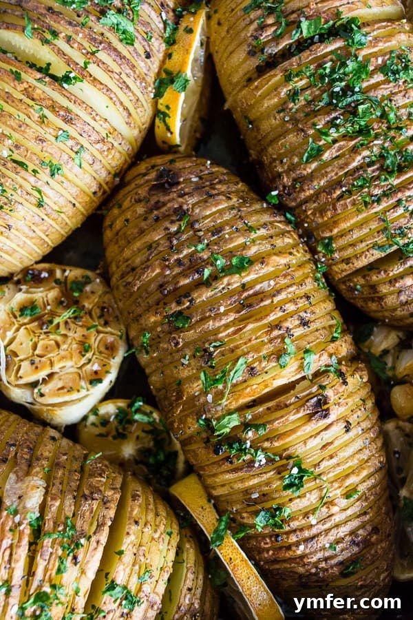 Zesty Herb Hasselback Roasties 4 Prepared Lemon Herb Hasselback Potatoes with lemon slices and garlic cloves, ready for the oven.