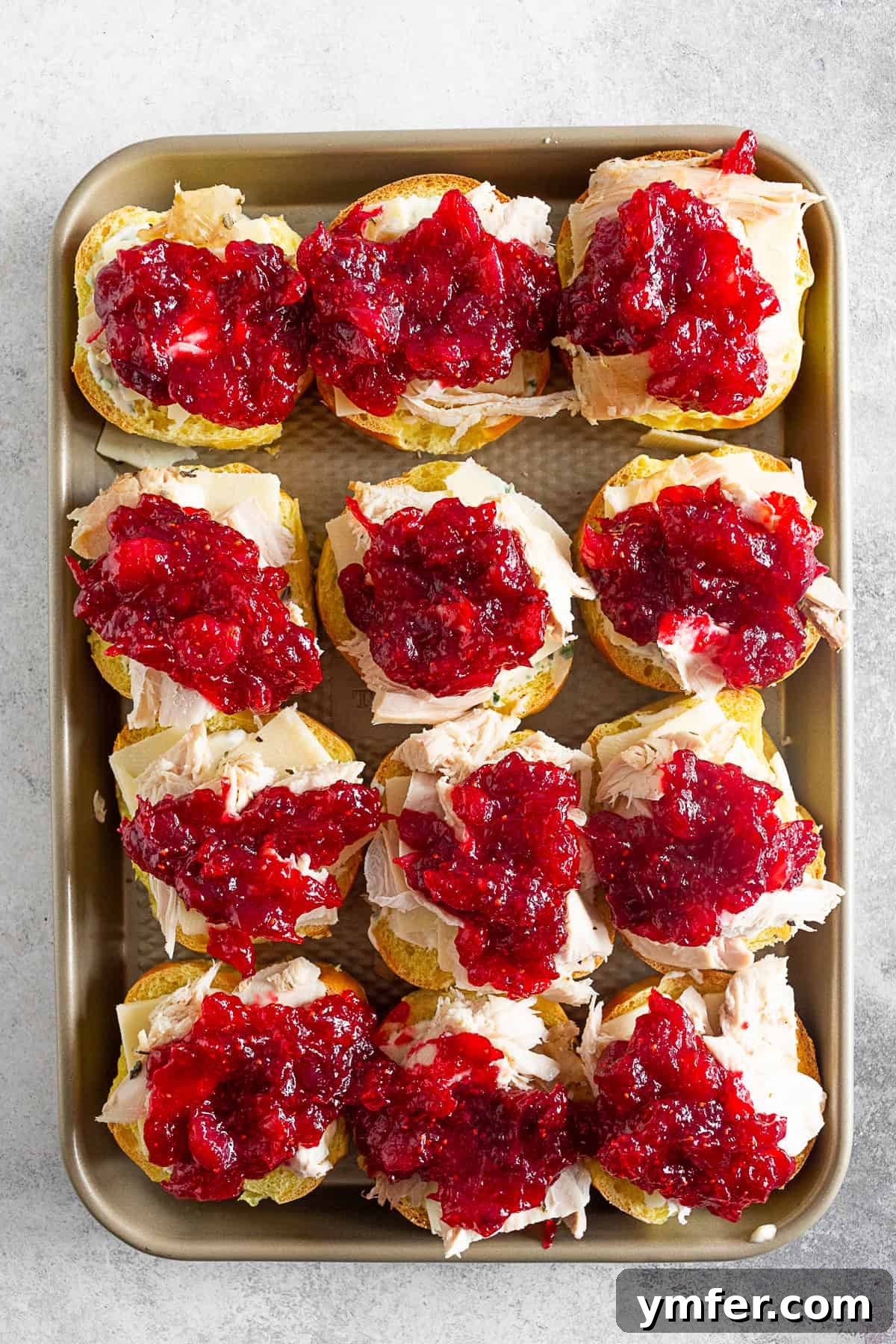 Roasted Turkey Cranberry Sandwich 3 Baked Cranberry Cheddar Turkey Sandwiches neatly arranged on a baking tray before cooking.