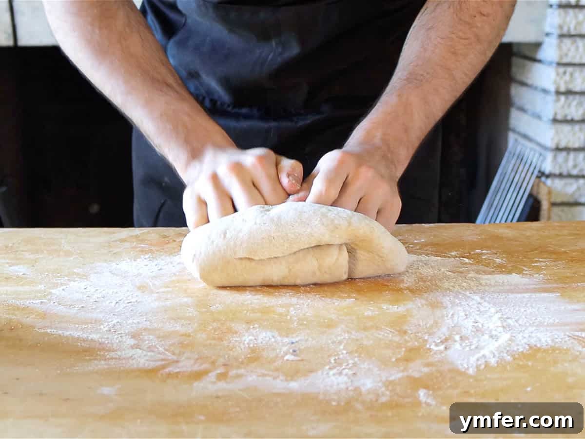 Heavenly Vegan Brioche 7 Hands actively kneading vegan brioche dough on a floured surface, demonstrating the development of its smooth texture.