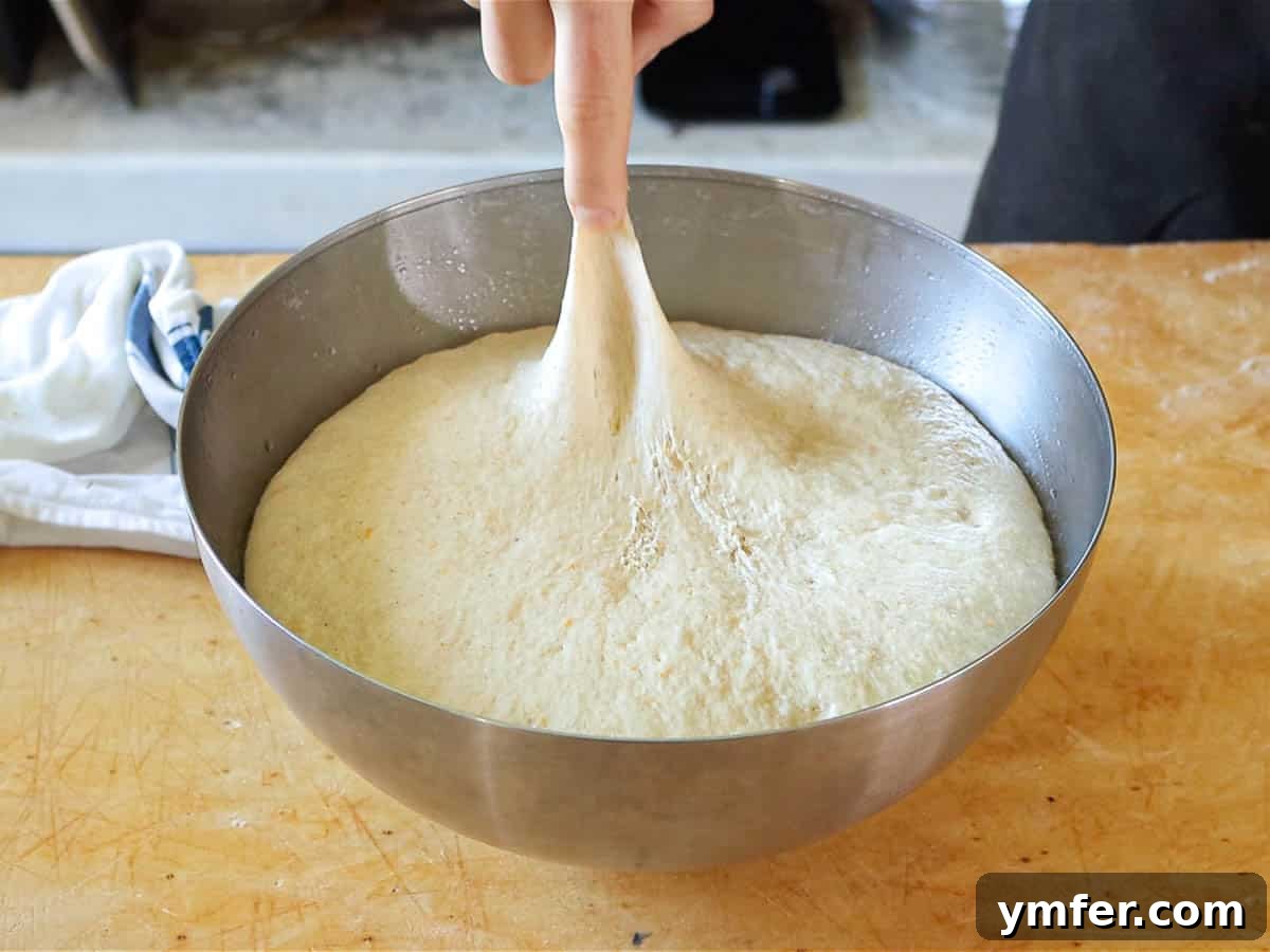 Heavenly Vegan Brioche 8 A finger gently pressing into fully proofed vegan brioche dough, showcasing its airy texture.
