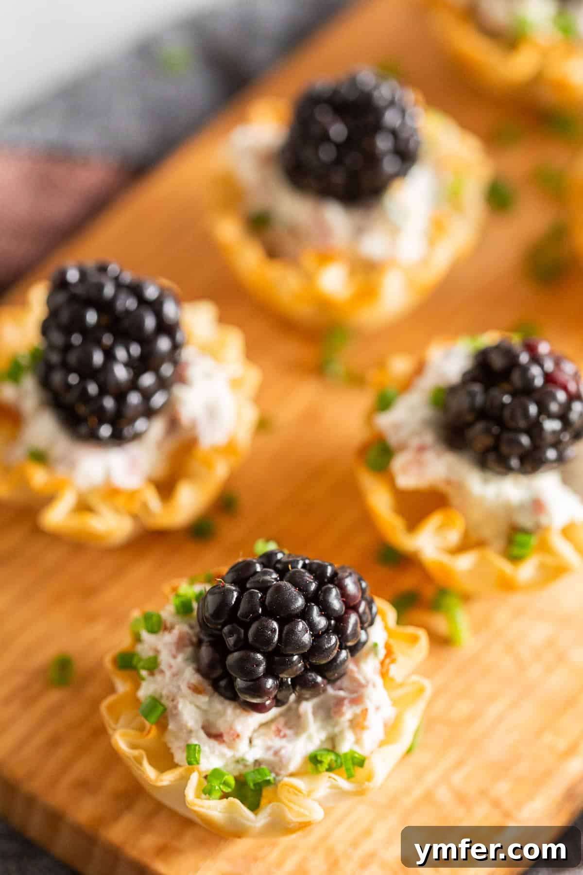 Golden Phyllo Goat Cheese Prosciutto Parcels 4 Goat Cheese Prosciutto Phyllo Bites garnished with finely chopped chives, showcasing the vibrant green against the creamy filling.