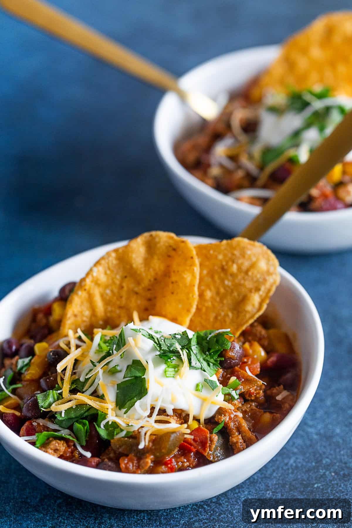 Smoky Chipotle Turkey Chili 2 Two small white bowls filled with steaming Chipotle Ground Turkey Chili, garnished with fresh cilantro, showcasing its rich texture and inviting warmth.