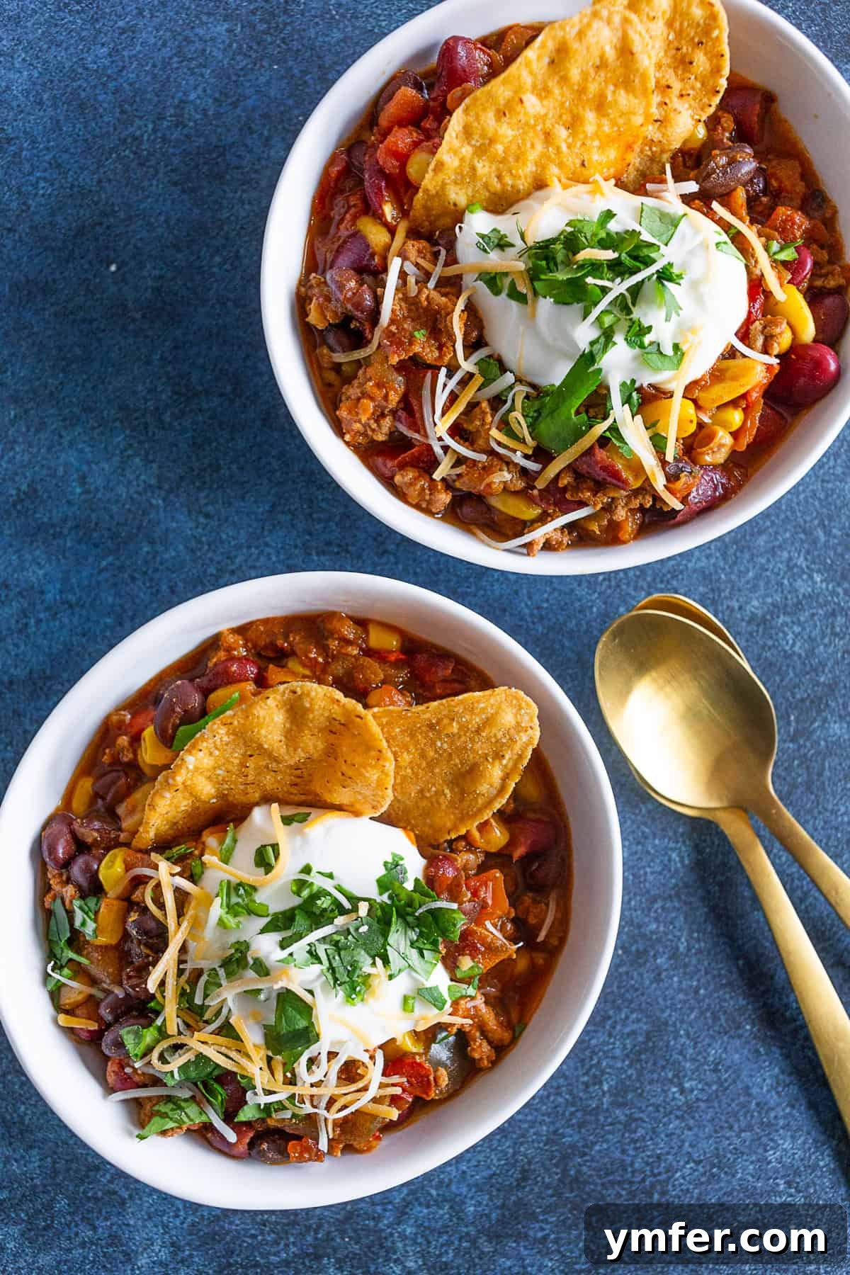 Smoky Chipotle Turkey Chili 3 A small white bowl of Chipotle Ground Turkey Chili topped with a swirl of sour cream and a generous sprinkle of fresh cilantro, ready to be enjoyed.