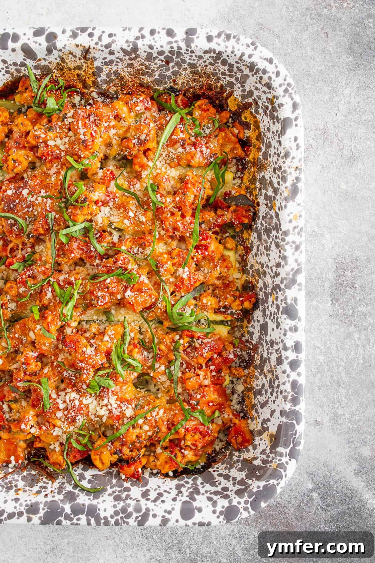 Cheesy Chicken Parm Zucchini Boats 4 Ground Chicken Parmesan Stuffed Zucchini Boats arranged neatly in a casserole pan before baking, showcasing their readiness for the oven.