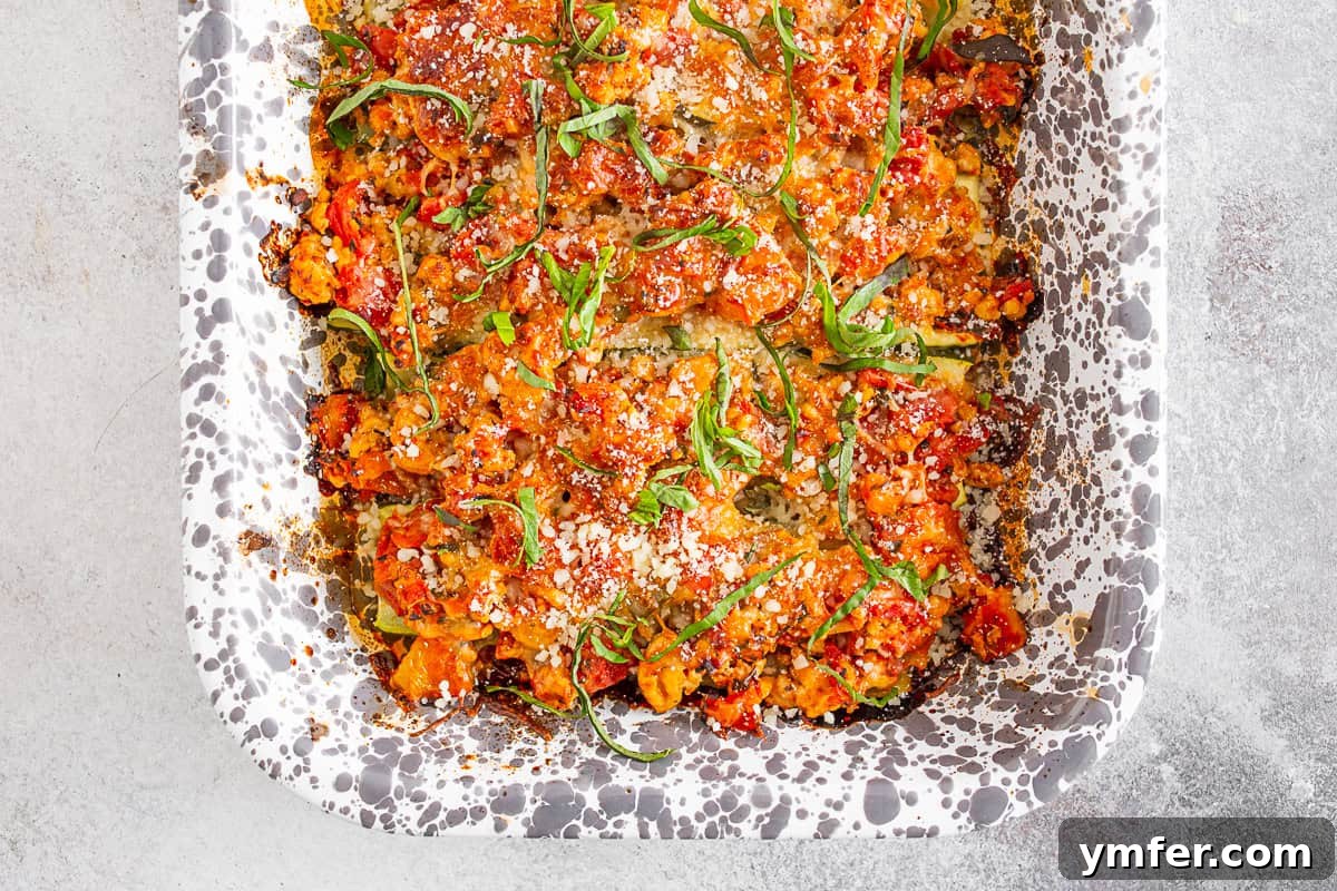 Cheesy Chicken Parm Zucchini Boats 6 Ground Chicken Parmesan Stuffed Zucchini Boats in a baking dish, freshly out of the oven, with melted cheese and rich filling visible.